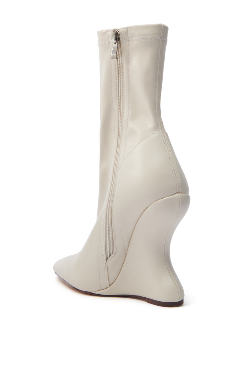 The AZALEA WANG ARKETTA bootie in cream faux leather has a side zipper, pointed toe, and a unique sculptural wedge heel. The sole is brown. 4