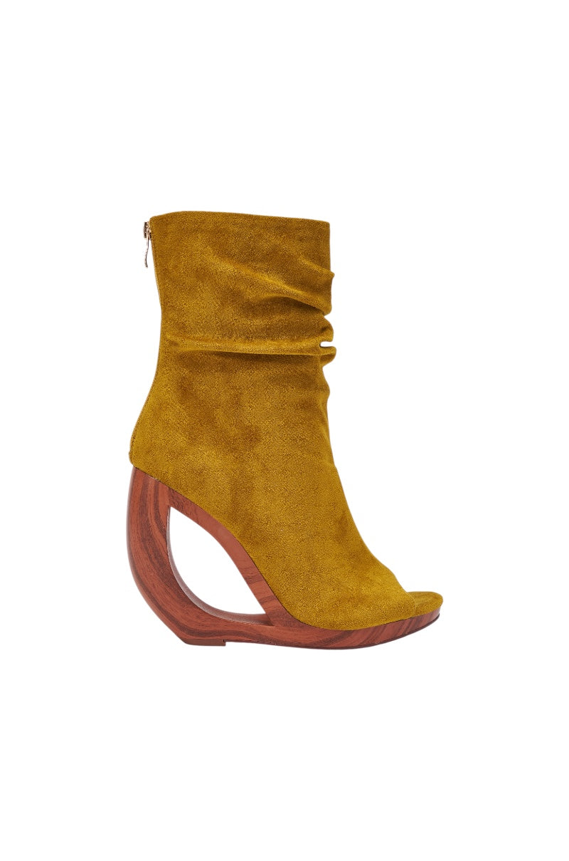 The AZALEA WANG ARLO Mustard Wedge Open Toe Faux Suede Bootie features a slouchy shaft, peep toe, and a curved wooden wedge heel, shown in side view against a white background.