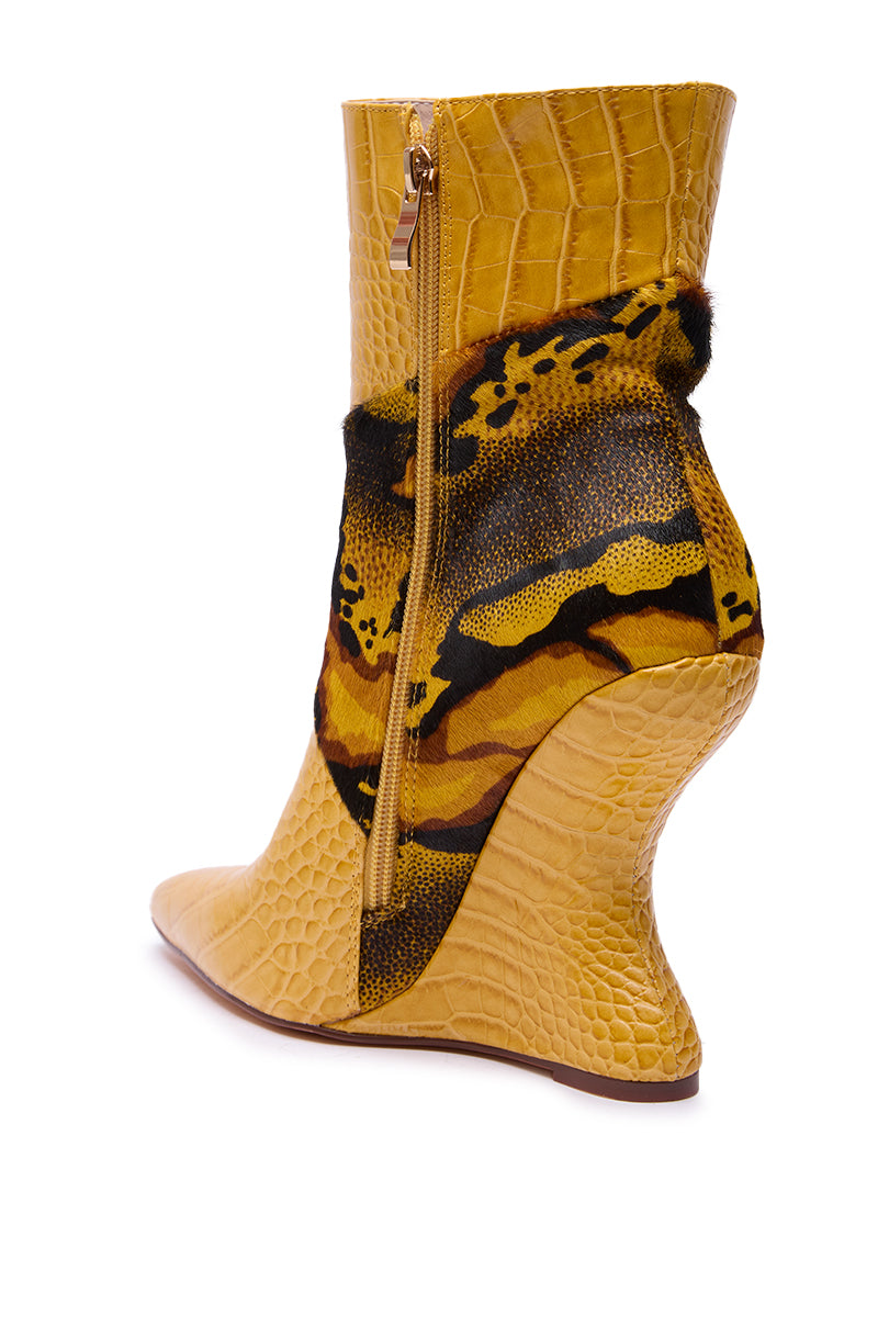 The AZALEA WANG ARTOUL YELLOW COLOR BLOCKED YELLOW WEDGE BOOTIE features faux leather with a crocodile pattern, an angular sculpted heel, side zipper, and bold black and brown abstract accents across the middle.