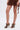 A woman wearing a brown lace skirt and the AZALEA WANG ASHLIE Color Blocked Snake Sandal stands against a plain white background, with only her legs and part of her skirt visible.