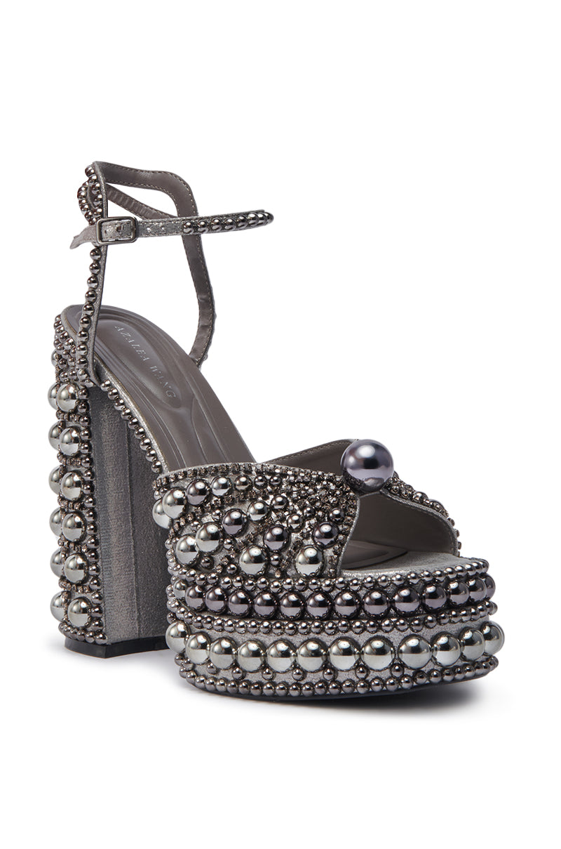 The AZALEA WANG ASTRELLA HEMATITE EMBELLISHED SANDAL features a chunky heel, ankle strap, and a mix of metallic and pearl-like beads for a bold, glamorous look.