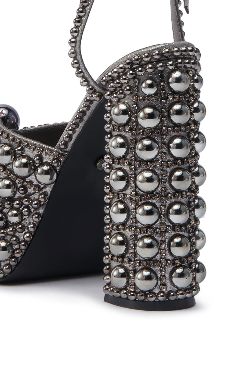 Close-up of the AZALEA WANG ASTRELLA HEMATITE EMBELLISHED SANDAL, featuring a chunky heel and surface adorned with shiny silver studs and round metallic beads.