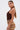 A woman with long, straight hair in a low ponytail wears large hoop earrings, a patterned mini skirt, and the GROOVING AND MOVING BODYSUIT. She stands in profile against a plain white background.
