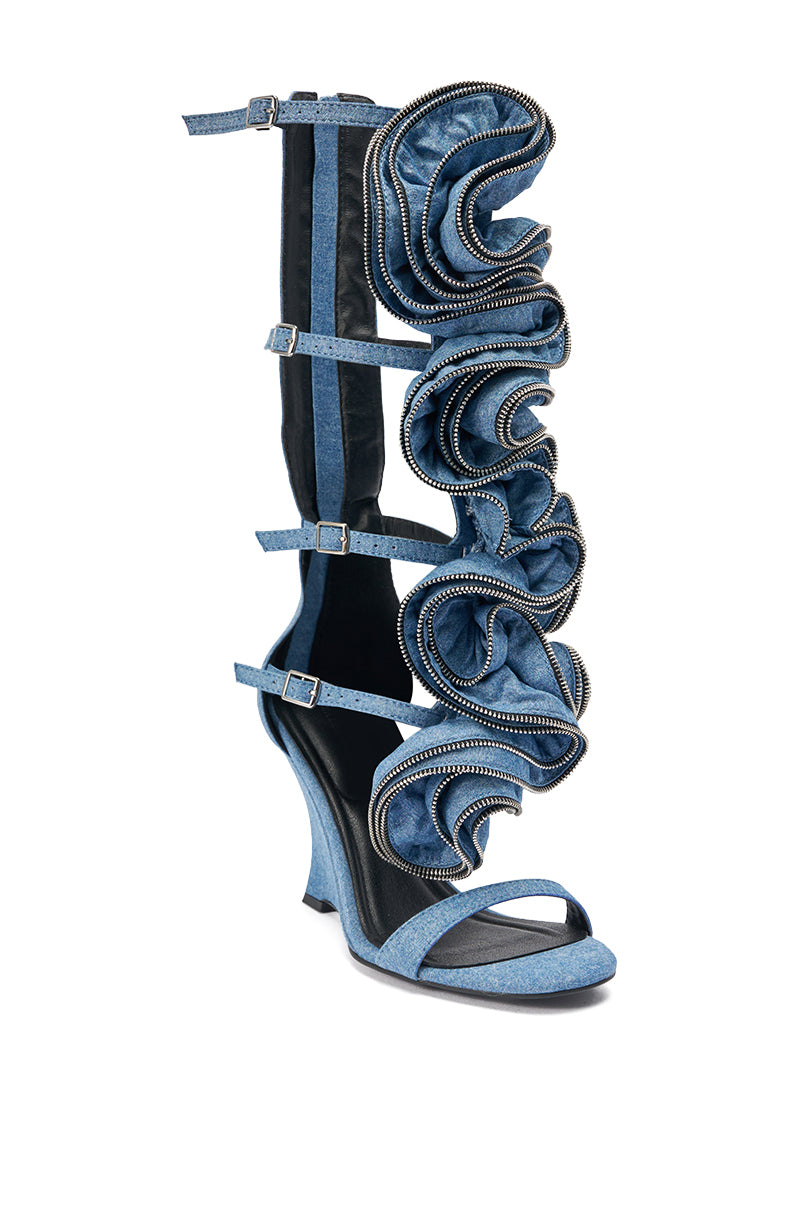 The AZALEA WANG ATLANTIC DENIM GLADIATOR WEDGE is a high-heeled, open-toe sandal with multiple straps, sculpted ruffle details, edge zippers, and a knee-high silhouette for an eye-catching statement look.