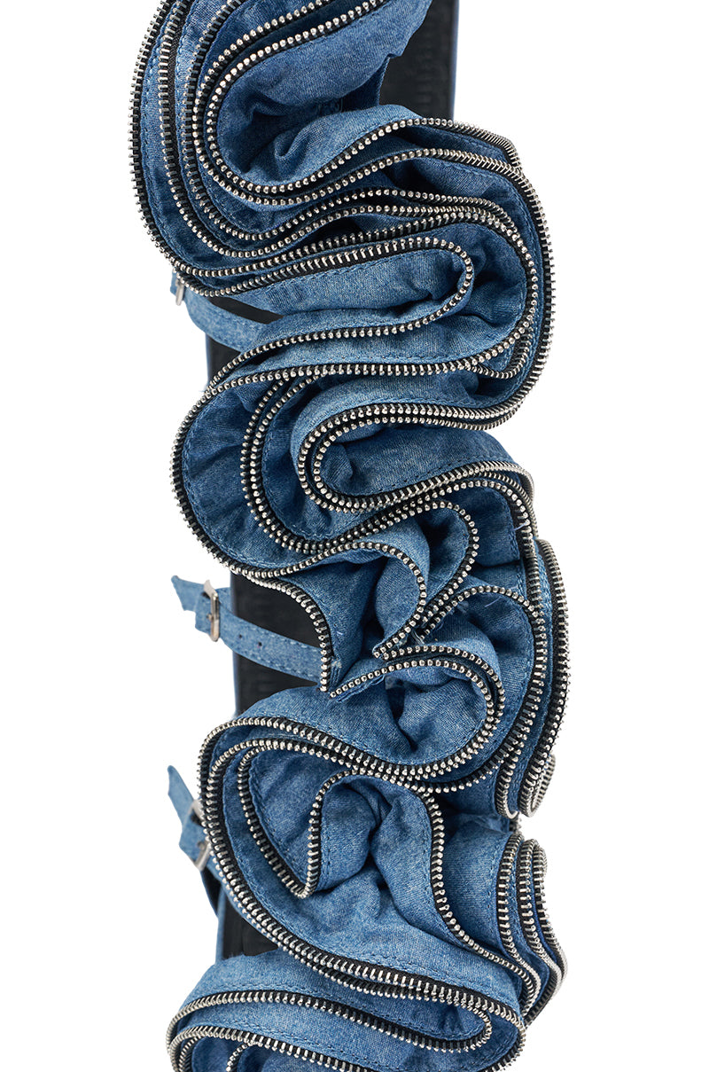 A close-up of layered blue denim with silver zippers, artfully ruffled in swirling shapes, reminiscent of sculpted ruffle detailing on the AZALEA WANG ATLANTIC DENIM GLADIATOR WEDGE.