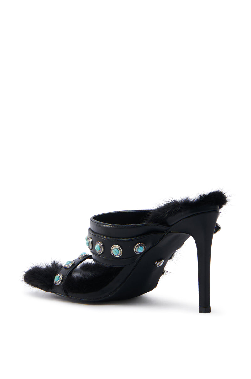 The AZALEA WANG AUGER BLACK SANDAL is a stylish black high-heeled mule with stiletto heel. It features two foot straps adorned with round turquoise stone embellishments and a fluffy trim, complemented by an open square toe for a chic finish.