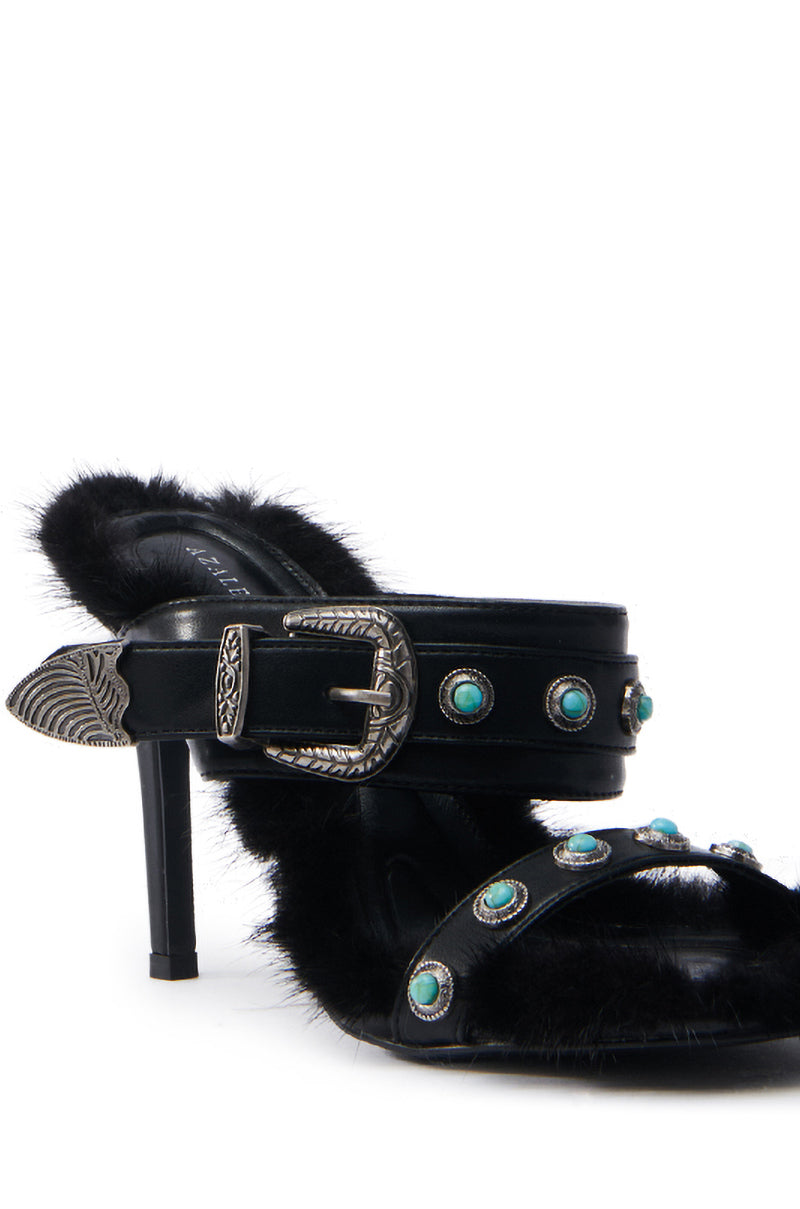 The AZALEA WANG AUGER BLACK SANDAL is a high-heeled vegan leather sandal with black fur details. It has embellished straps with silver buckles, turquoise studs, a pointed metallic toe accent, and a chic stiletto heel.