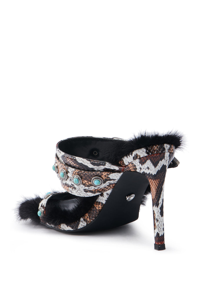 The AZALEA WANG AUGER BROWN SANDAL showcases a stunning snakeskin pattern, adorned with turquoise stones and black fur trim. Made from vegan leather, it features an open toe and a tall stiletto heel.