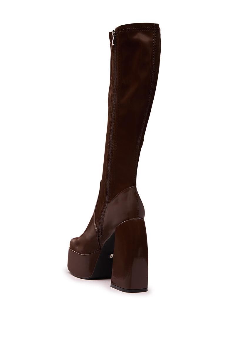The AZALEA WANG AURON BROWN LIQUID LUXE PLATFORM BOOT is a knee-high, brown faux patent leather boot with a high chunky heel, shiny finish, and side zipper, shown against a plain white background.