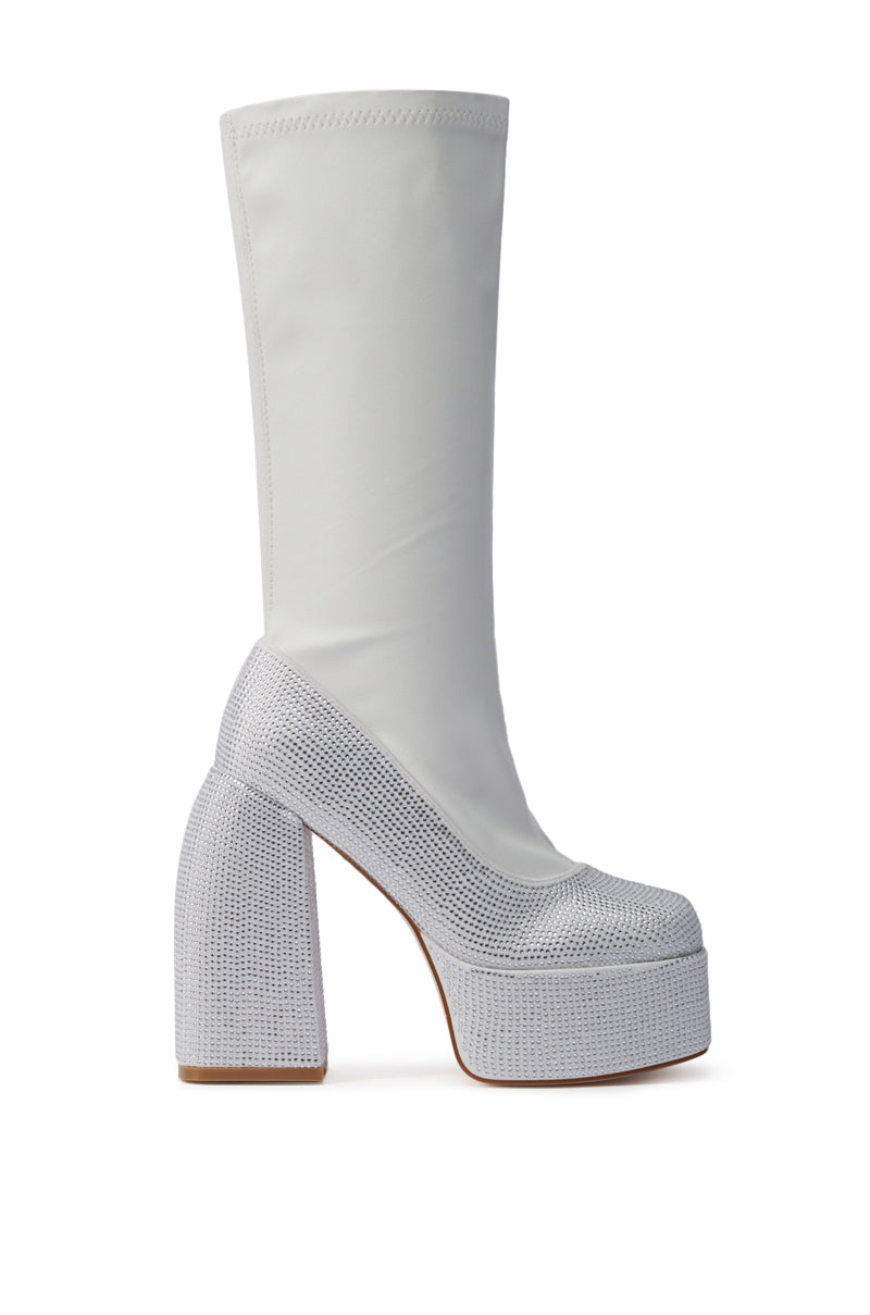 The AZALEA WANG AURONNE White and Rhinestone Chunky Boot is a knee-high faux leather platform with a thick block heel, rhinestone accents, and textured foot and heel details, shown in a side view against a plain background.
