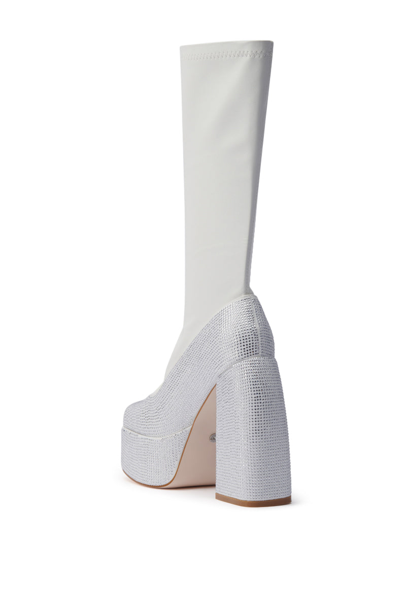 The AZALEA WANG AURONNE WHITE AND RHINESTONE CHUNKY BOOT features a high heel, platform sole, tall white stretchy shaft, and sparkly silver faux leather base and heel, shown from a rear side angle against a white background.