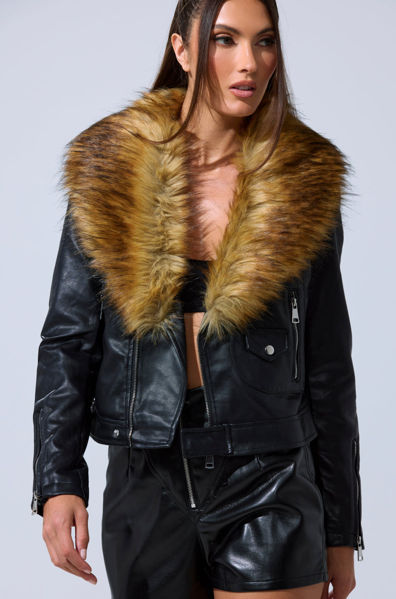 A woman models the AUSSY FUR COLLAR MOTO, a chic black faux leather jacket with a large detachable fur collar, paired with matching shorts against a plain light background.