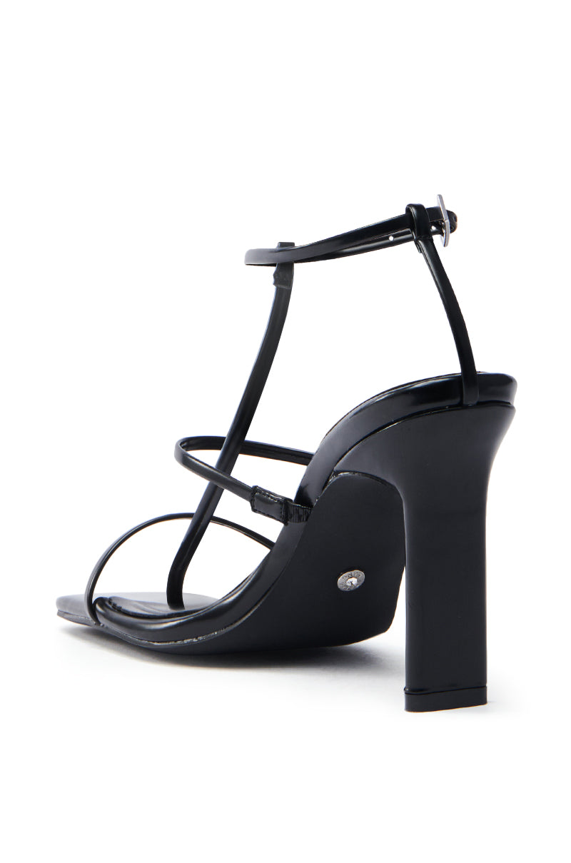 The AZALEA WANG AVENA BLACK PAT SANDAL is a sleek black vegan leather high heel with thin ankle and foot straps, a block-shaped chunky heel, and a glossy finish.