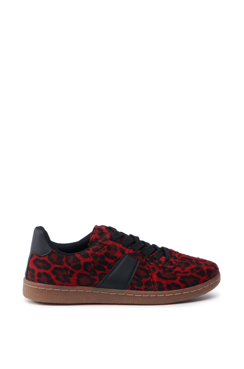 The AZALEA WANG AVENGER RED LEOPARD SNEAKER showcases a vibrant red and black leopard print adorned with black laces and a unique faux pony hair texture. This stylish low-top design includes a bold black side accent and is finished with a durable brown sole.