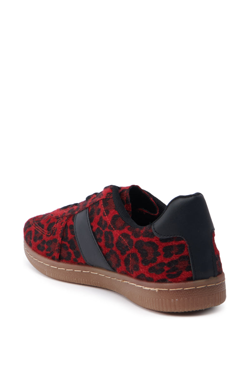 The AZALEA WANG Avenger Red Leopard Sneaker features a bold red and black leopard print, complemented by a sleek black stripe on the side and a durable brown rubber sole. It has a lace-up vamp and faux pony hair texture, with a stylish black heel accent seen from the back.