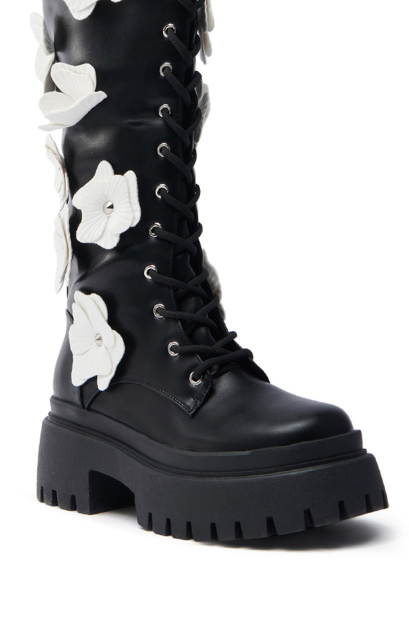 The AZALEA WANG MIRABELLA BLACK FLORAL EMBELLISHED BOOT is a bold, versatile knee-high with a chunky sole and lace-up front, crafted from faux leather and adorned with white flower appliques along the shaft.