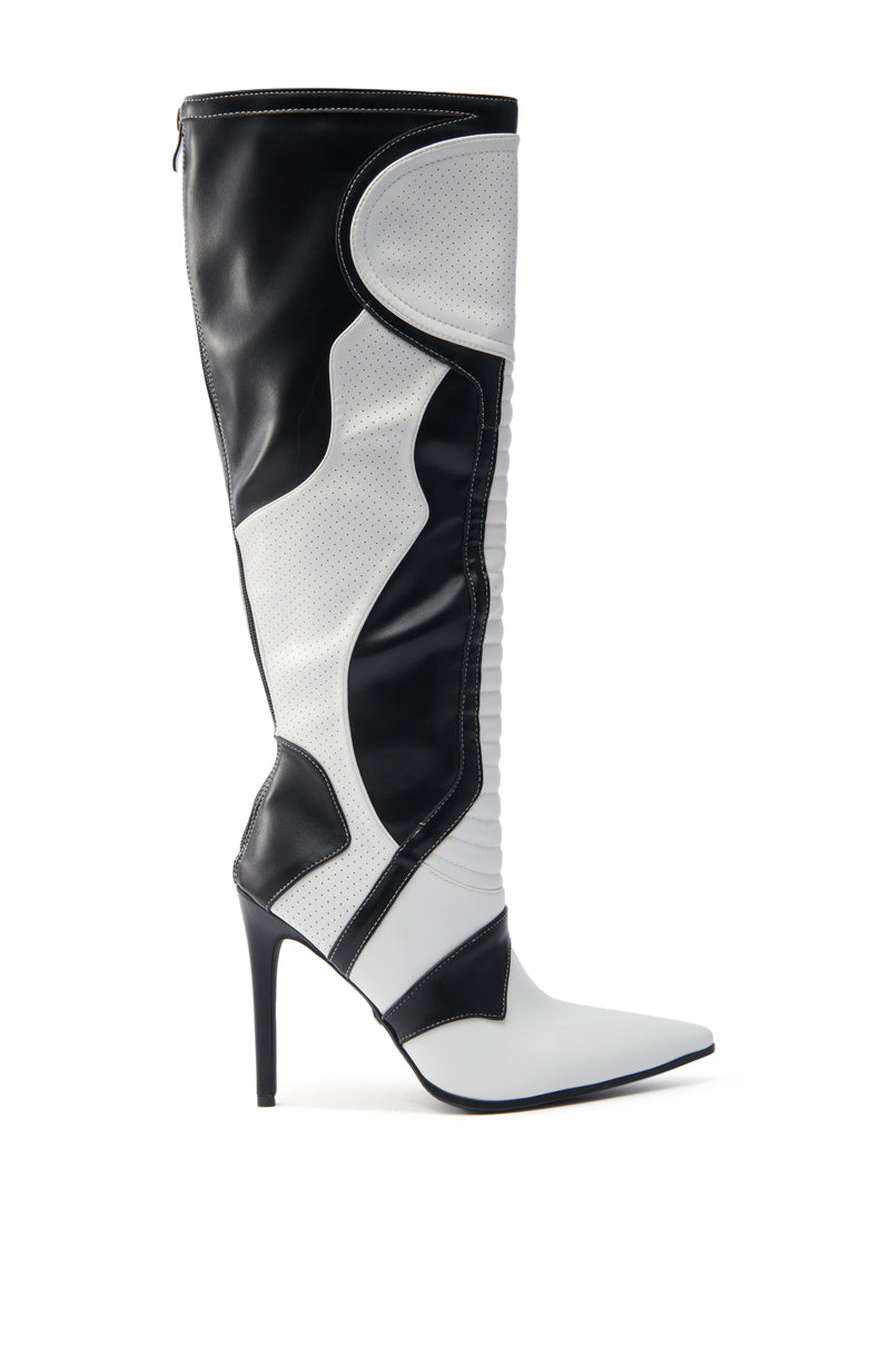 The AZALEA WANG RODRIGO BLACK AND WHITE BOOT STILETTO is a chic, high-heeled knee-high boot in vegan leather with a sleek design. It features two-tone contrasting panels, a pointed toe, and stiletto heel for a modern and bold look.