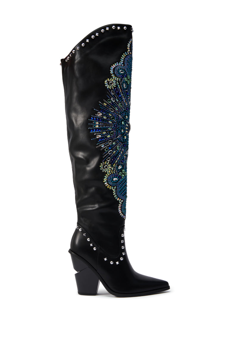 The AZALEA WANG AXELBEAT BLACK EMBELLISHED WESTERN BOOT is a black, knee-high leather Western boot with a pointed toe, chunky heel, blue and green jeweled floral embroidery, and silver studs on the top and sole.