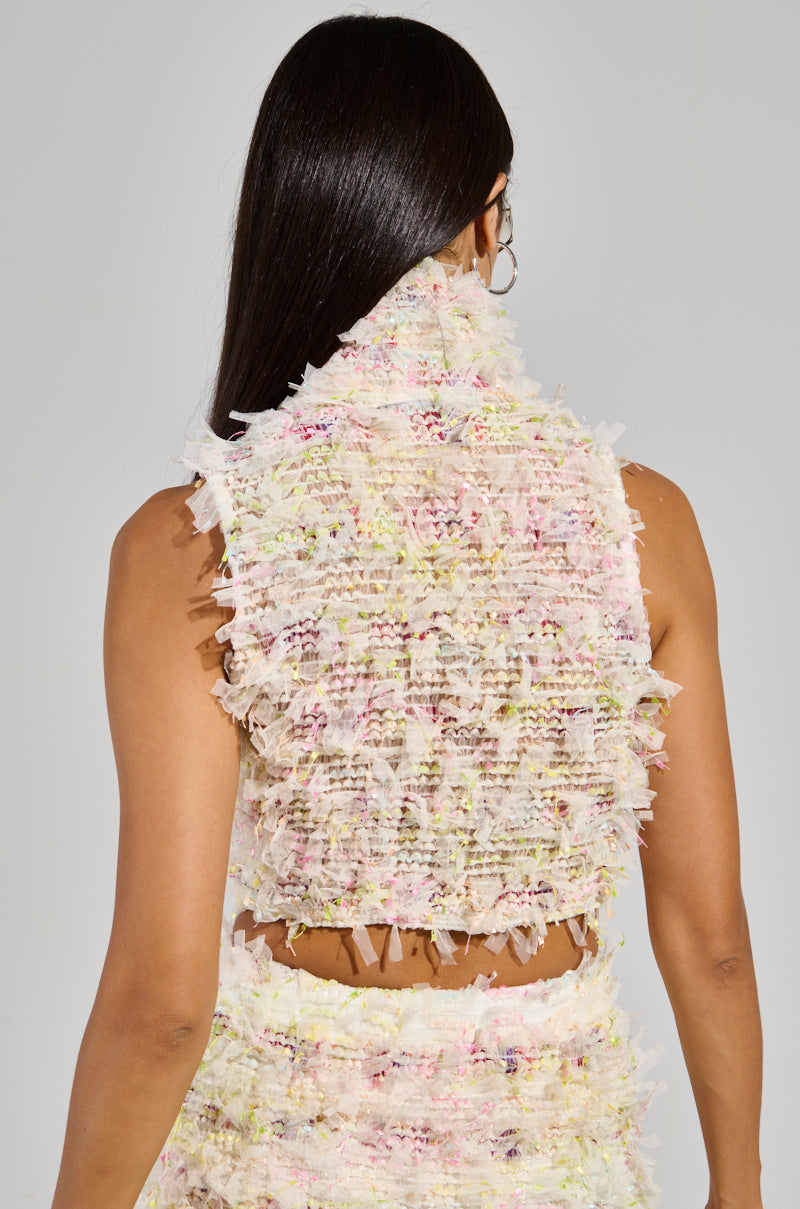 A person with long dark hair is pictured from behind, wearing a pastel-colored, textured SWEET LIKE CANDY SLEEVELESS TOP featuring fringed details. This cropped top is part of a matching set, set against a plain light gray background.