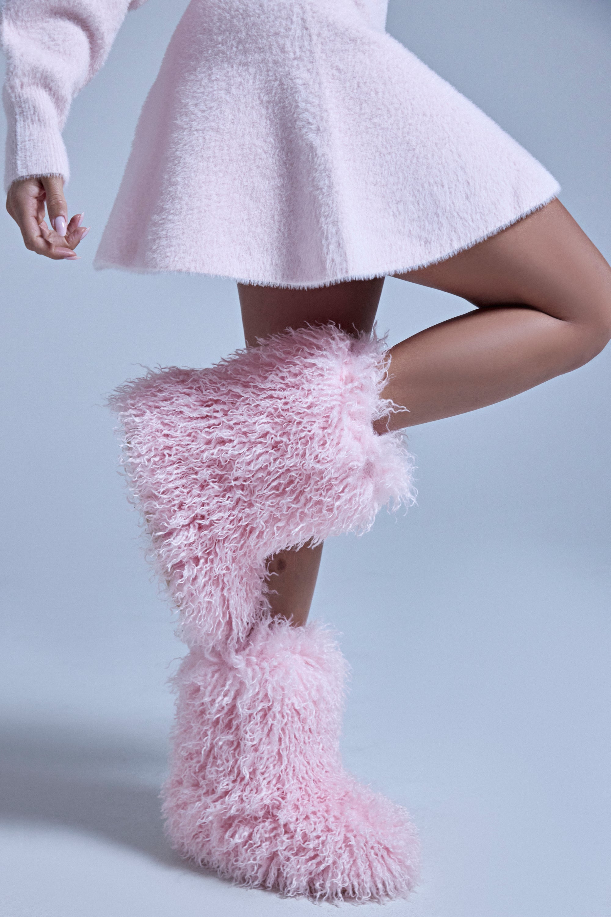 A person wears a textured light pink skirt and the AZALEA WANG AZAD PINK MOHAIR FLAT BOOTIE, posing with one leg bent against a plain light background.
