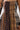 A close-up of a person in the FALL IN LOVE PLAID MAXI DRESS, a strapless maxi with mixed brown, black, and cream plaid patterns, gathered fabric, a black shoulder strap, and 90’s-inspired punk princess vibes.
