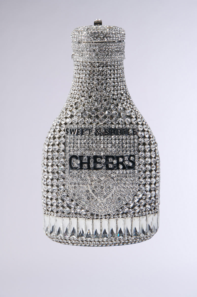 Introducing the CHEERS BLING PURSE, a unique bottle-shaped clutch that dazzles with silver rhinestones. It showcases the words "Sweet & Subtle" and "Cheers" set against a gradient gray background, making it perfect for those who appreciate a touch of flair. 0