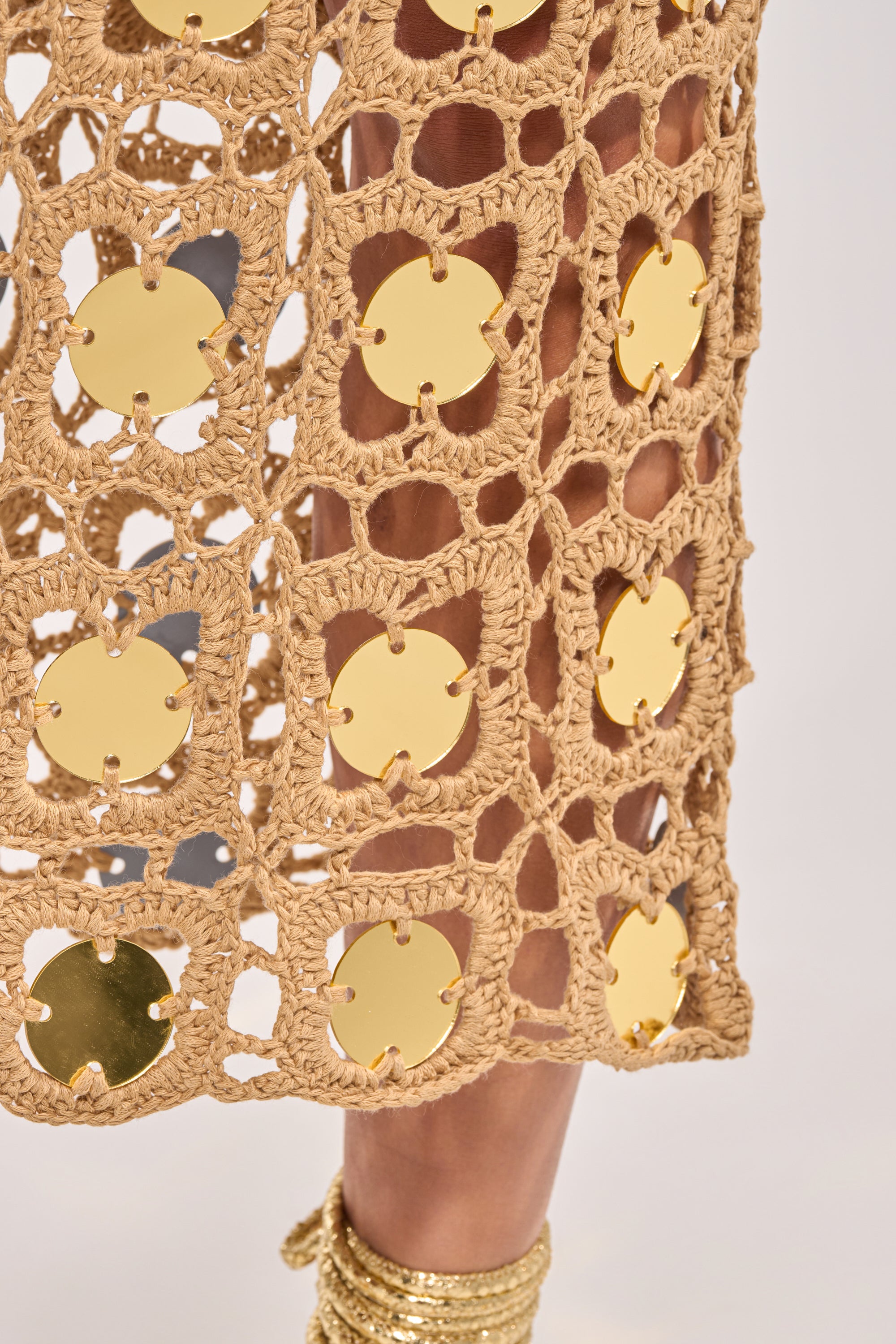 Close-up of the HOT GIRL AGENDA SEQUIN CROCHET MIDI DRESS in beige, detailed with gold disc sequins, styled with gold wrapped sandals for a chic beach-glam look. 5