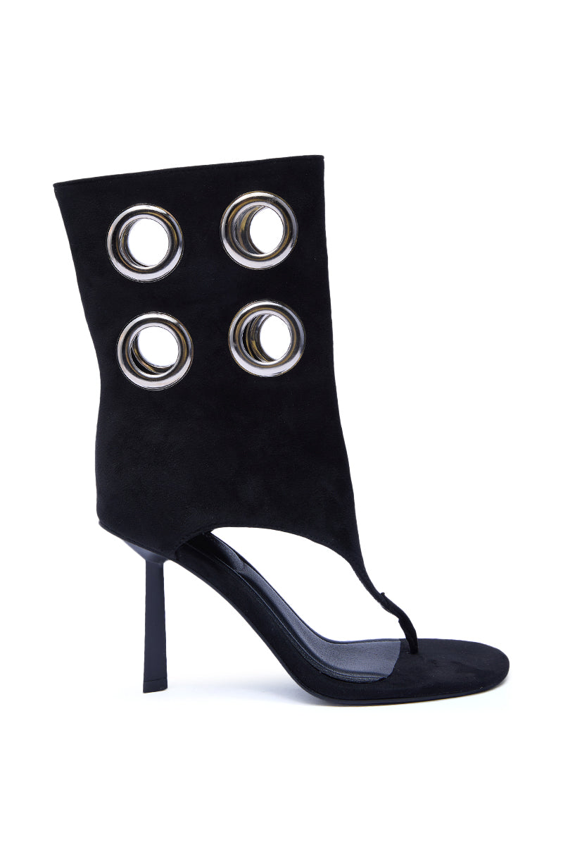The AZALEA WANG BAINA BLACK GROMMET DETAIL GLADIATOR SANDAL is a black high-heeled sandal with an open toe, high ankle cuff, four metallic grommets on the ankle strap, and a sleek stiletto heel for a bold, modern style.