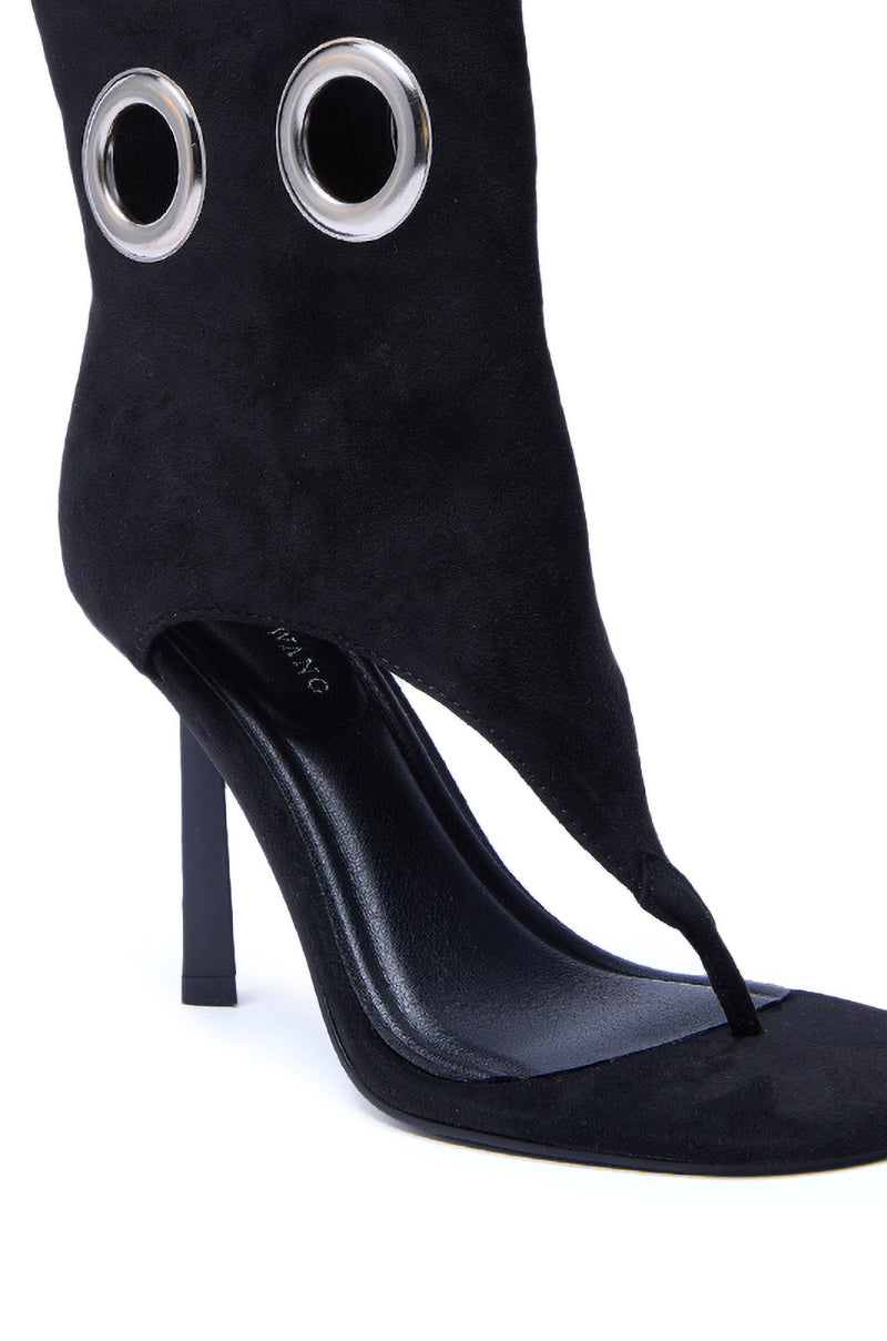 The AZALEA WANG BAINA BLACK GROMMET DETAIL GLADIATOR SANDAL is a black suede stiletto sandal with an open toe, thong strap, unique grommet accents on the upper, and a bold design for standout style.