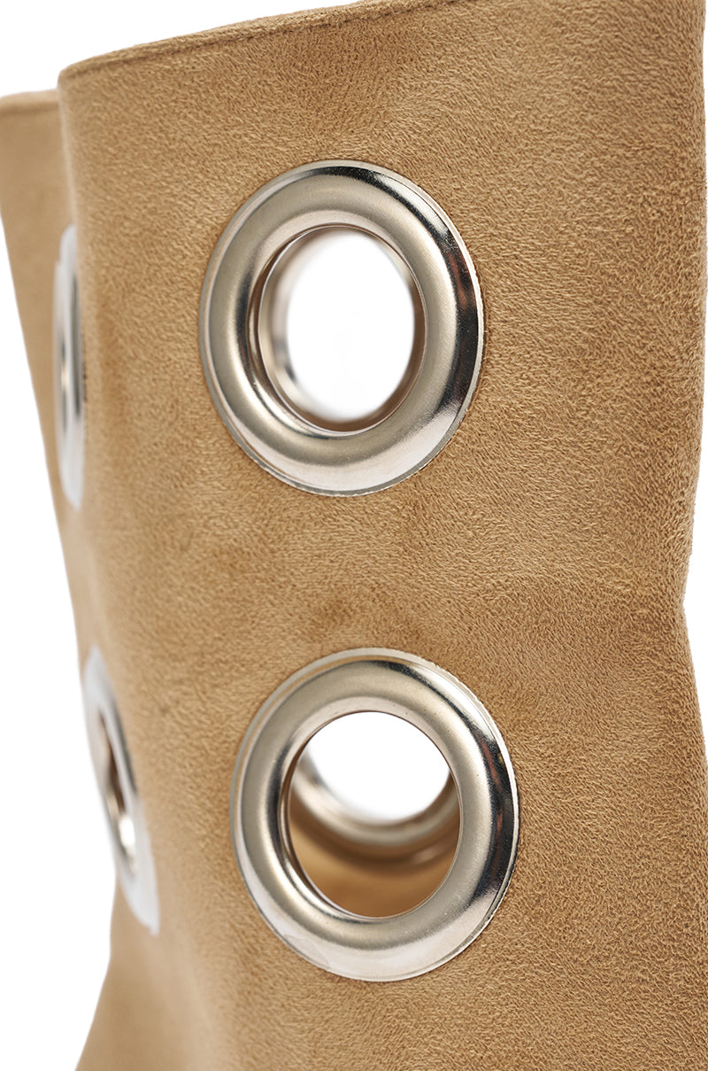 Close-up of tan faux suede on the AZALEA WANG BAINA TAN SILVER HARDWARE STILETTO SANDAL featuring large silver grommets, showcasing textured material and bold circular hardware accents.