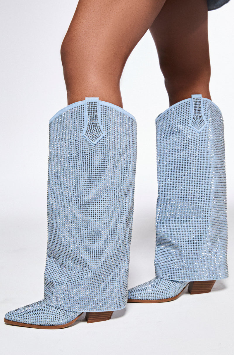 Someone stands on a white background wearing the AZALEA WANG BANIAN DENIM WESTERN RHINESTONE BOOTS, which feature eye-catching sparkly light blue denim and a chunky heel, covered in dazzling shimmering sequins.
