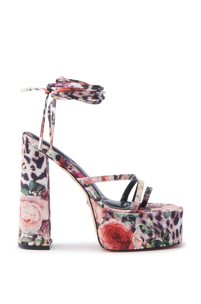 The AZALEA WANG BANIRA MULTI CHEETAH FLORAL CHUNKY SANDAL features a high block heel, satin textile upper, strappy design, and ankle tie. It's adorned with pink and red roses along with muted leopard print accents.