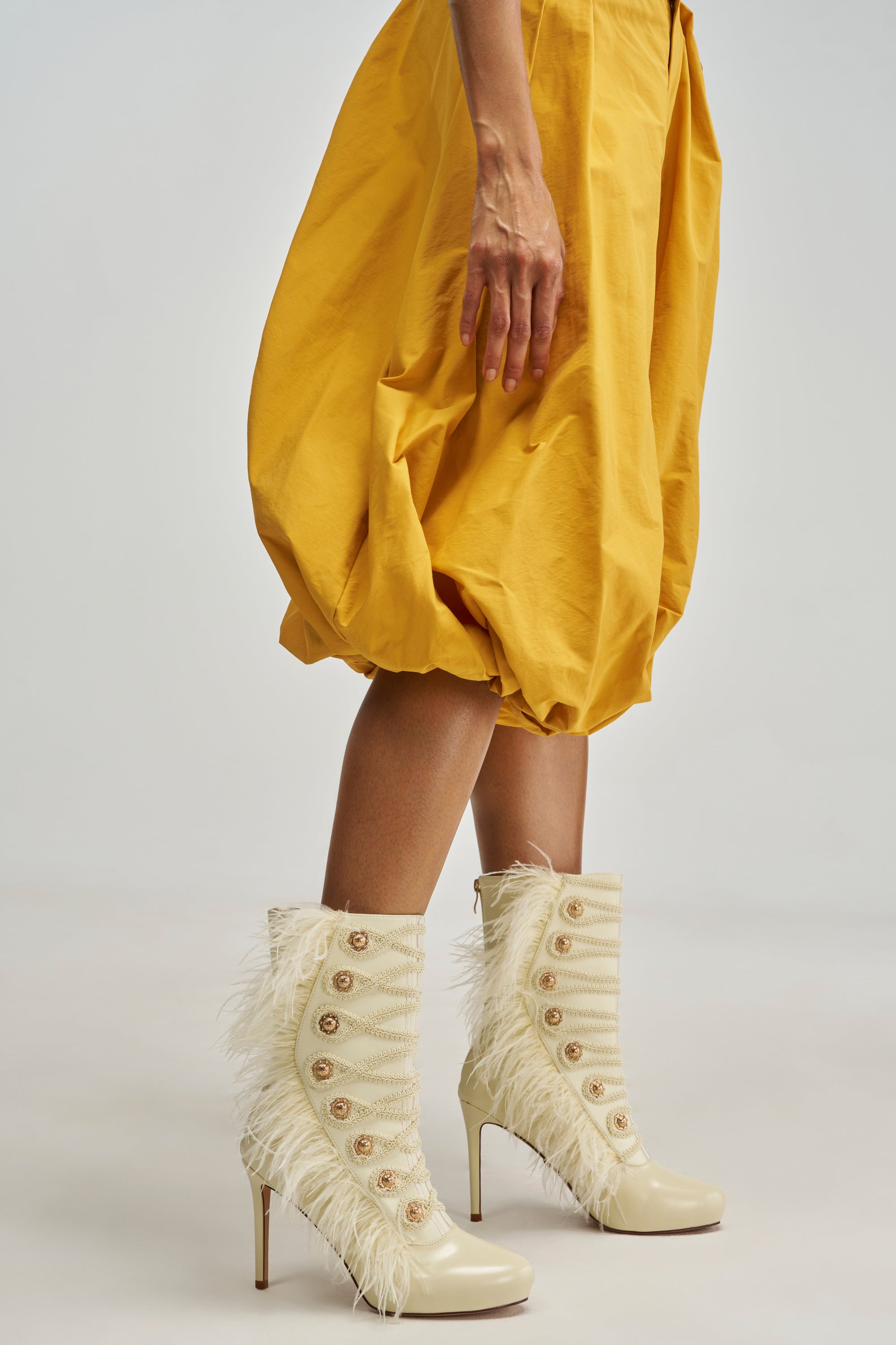 AZALEA WANG BANSHEE IVORY MILITARY AND FEATHER STILETTO BOOTIES in ivory with feathered trim and rows of gold military-style buttons.