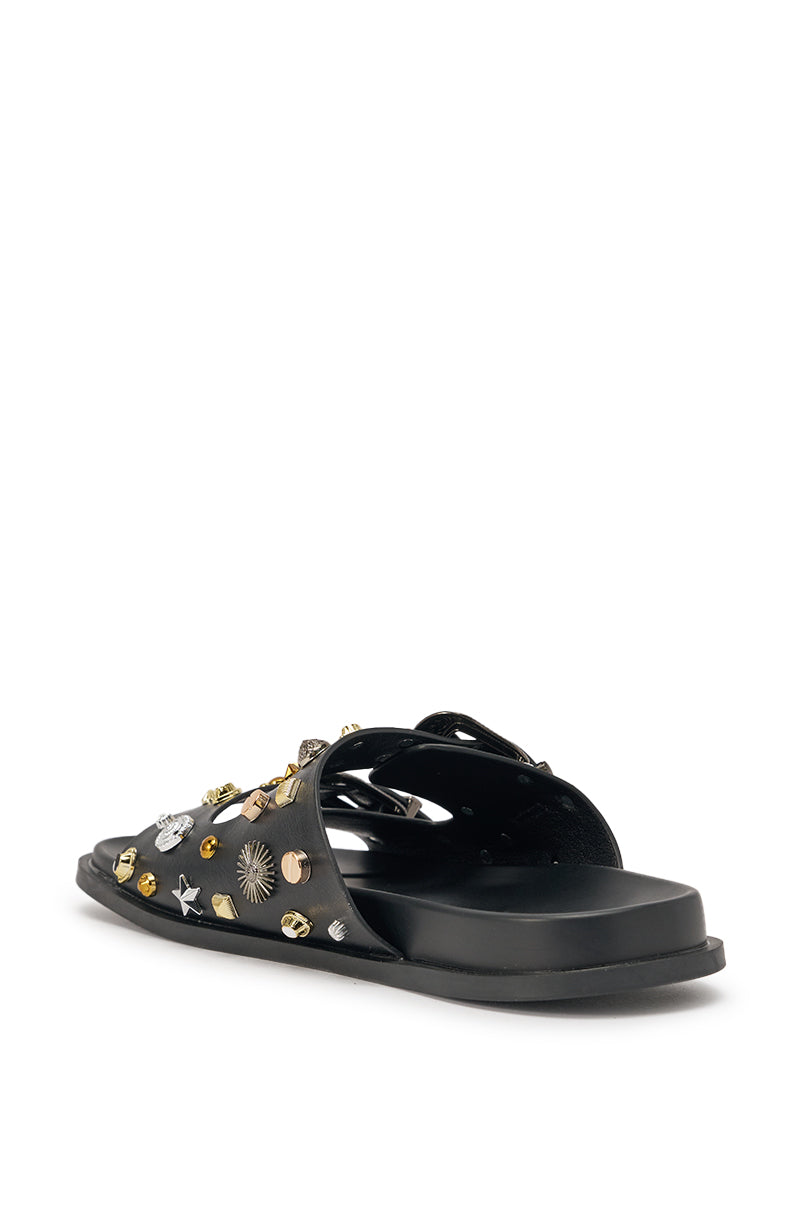 The AKIRA BARCLAY BLACK METAL EMBELLISHED SLIP ON FLAT SANDAL features black faux leather, gold and silver studs with star accents, a flat sole, and western-inspired style, shown from the back left on a white background. 6