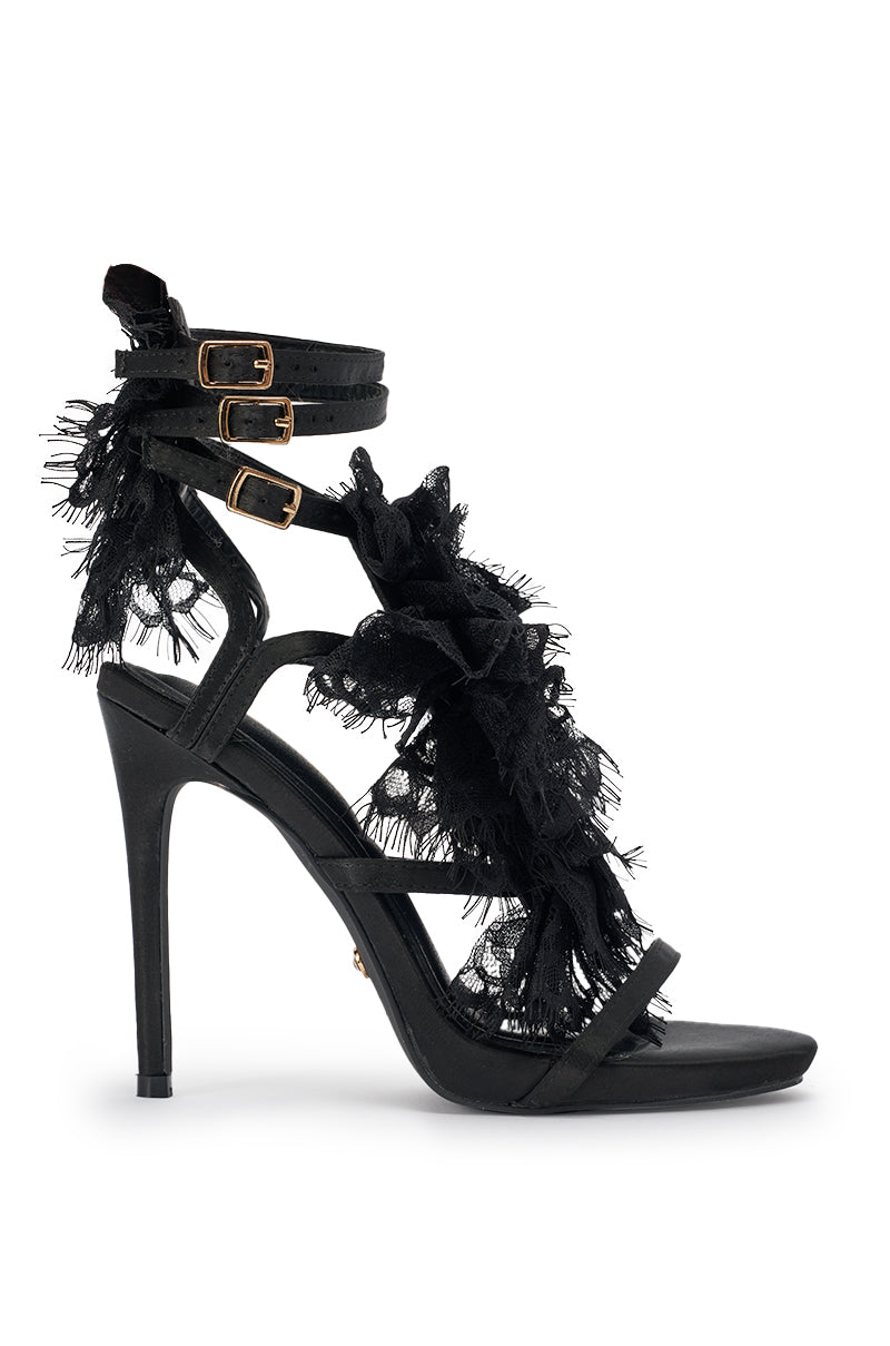 The AKIRA GOLD BARRISTER Black Lace Detail Stiletto Sandal features black satin, two gold ankle buckles, ruffled lace trim on the front and sides, and a slim strap across the open toe for an elegant finish. 3