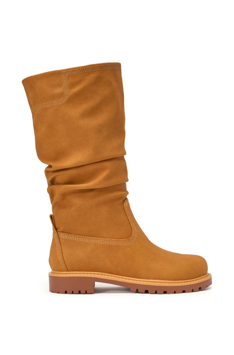 The AKIRA GOLD BARTLETT TAN FLAT RUCHED BOOTIE features tan faux leather, a ruched shaft, round toe, visible stitching, and a chunky treaded rubber sole. Shown in side profile on a white background. 4
