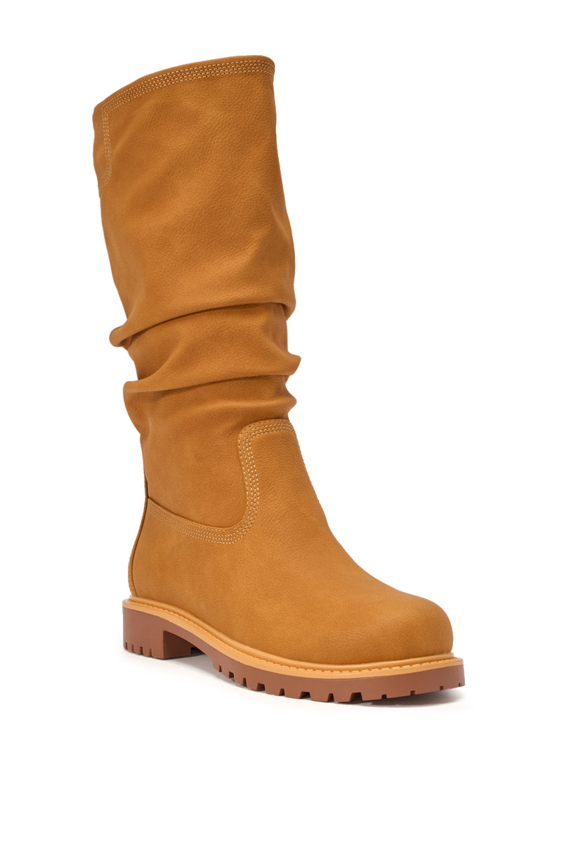 The AKIRA GOLD BARTLETT TAN FLAT RUCHED BOOTIE is a single mid-calf bootie featuring a tan ruched shaft, round toe, visible stitching, and a flat ridged sole. 5