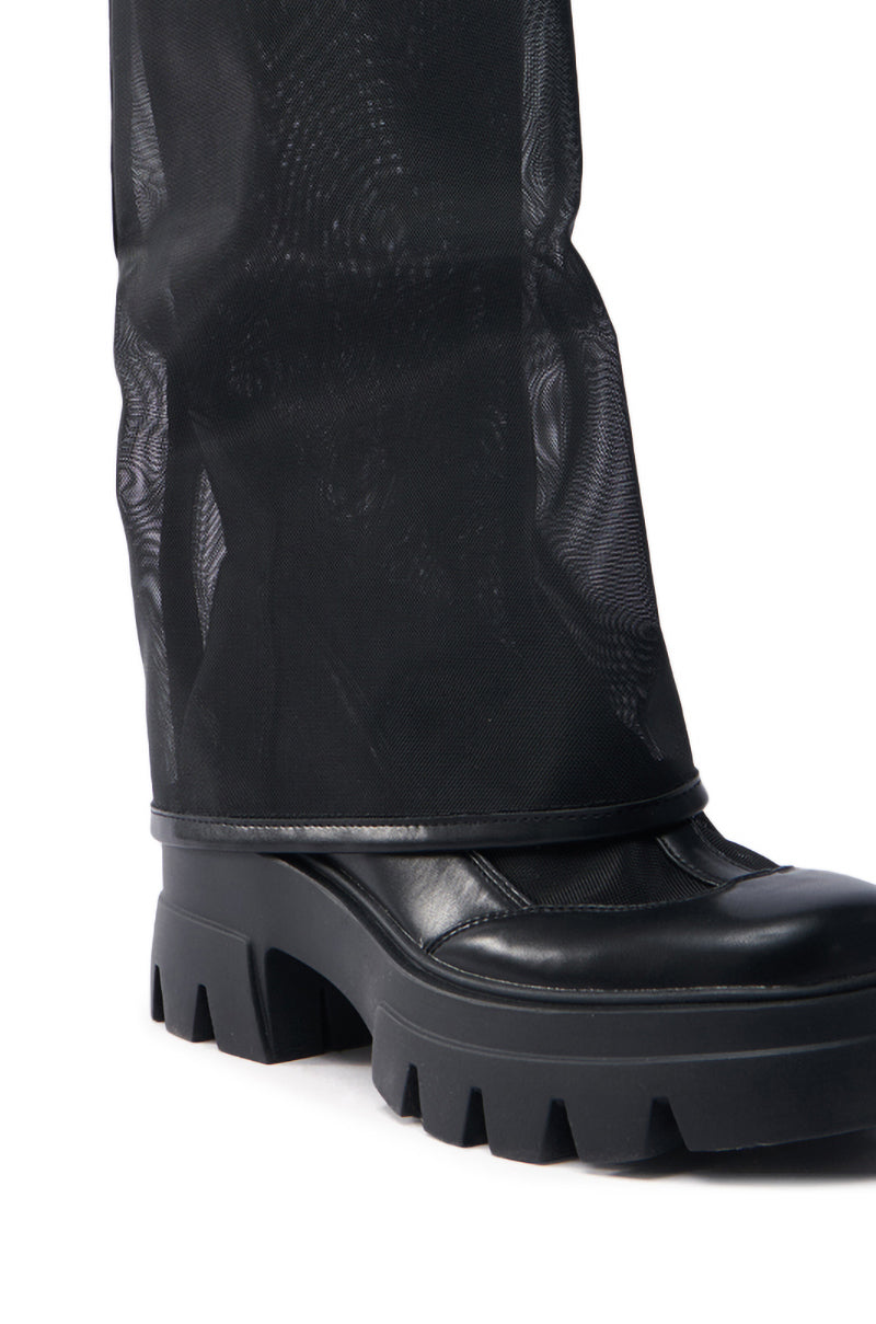 The AZALEA WANG BAYE BLACK MESH BOOT, pictured in close-up, highlights its chunky ridged sole and mid-calf design. The boot's tall sheer black mesh extends upwards, adding a modern and edgy touch.