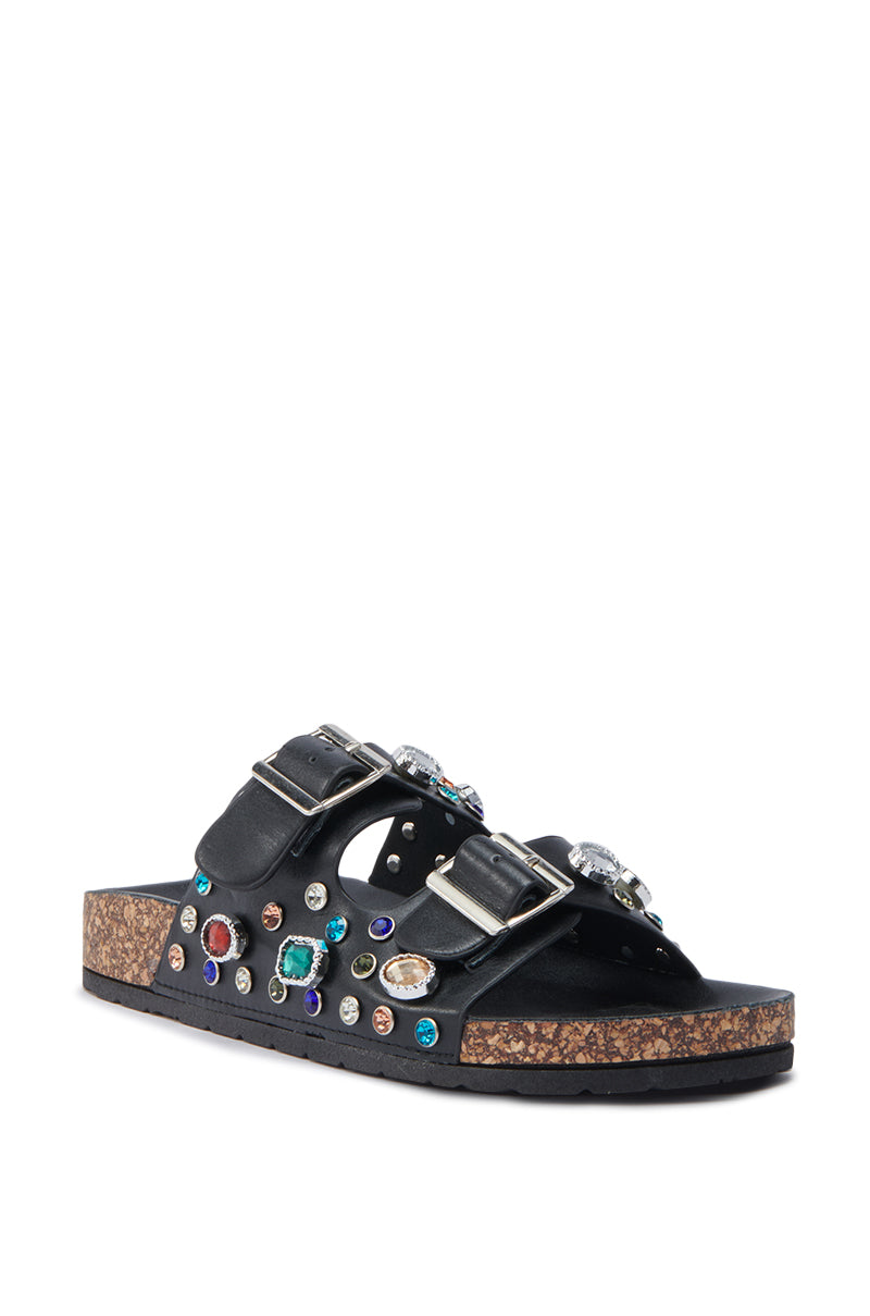 The AKIRA BAYLEAVES SLIP ON BLACK SANDAL features black faux leather, two adjustable buckle straps with gemstone accents, and a comfortable cork sole.
