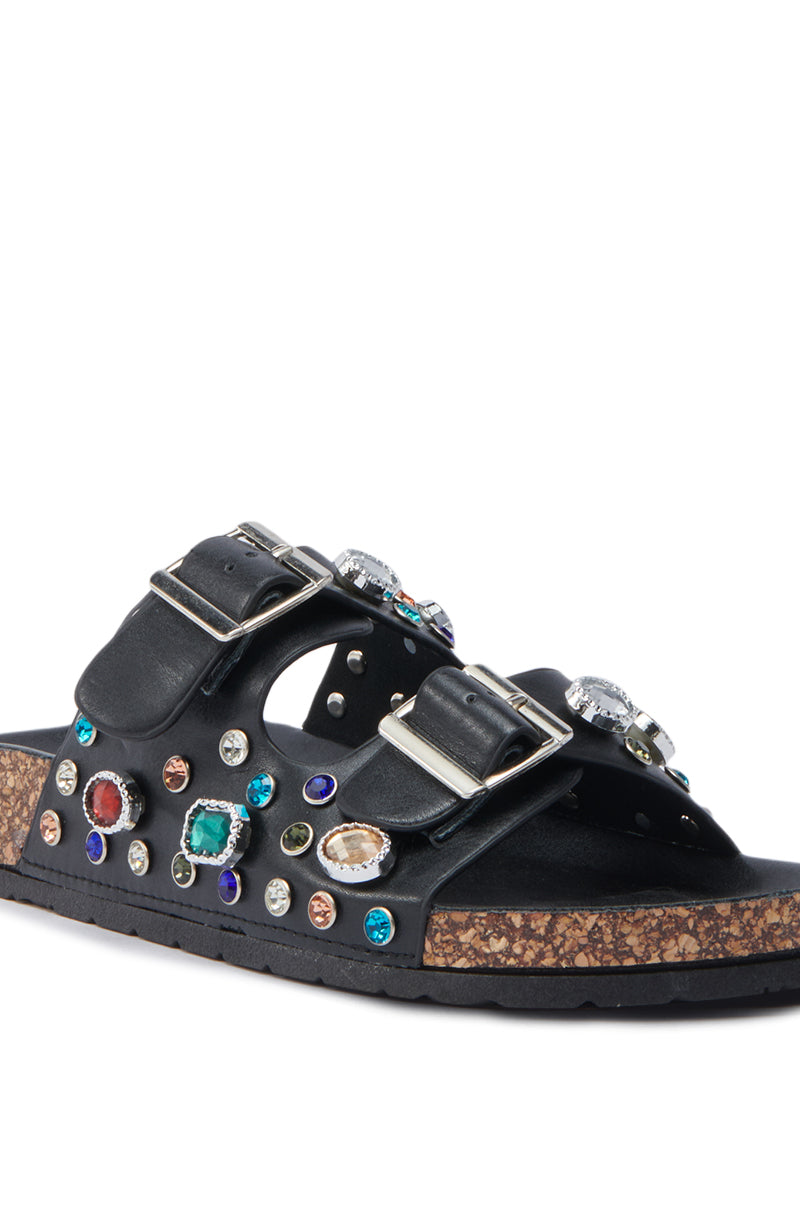 The AKIRA BAYLEAVES SLIP ON BLACK SANDAL features two large faux leather buckle straps, adorned with colorful gemstone details and a cork-textured sole for stylish, vibrant flair.
