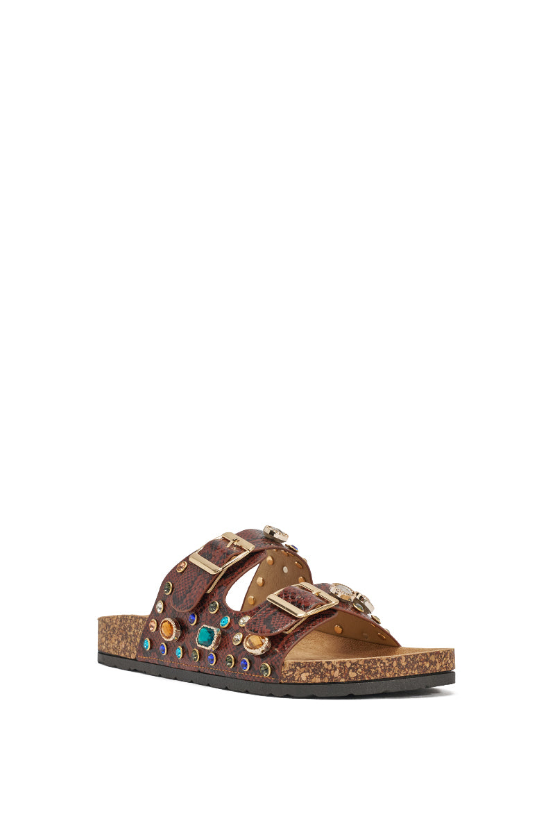The AKIRA BAYLEAVES Brown Snake Embellished Flat Slip On Sandal features a brown faux leather upper, cork sole, two adjustable straps, and is adorned with colorful studs, metallic accents, and rhinestones, shown on a white background. 7