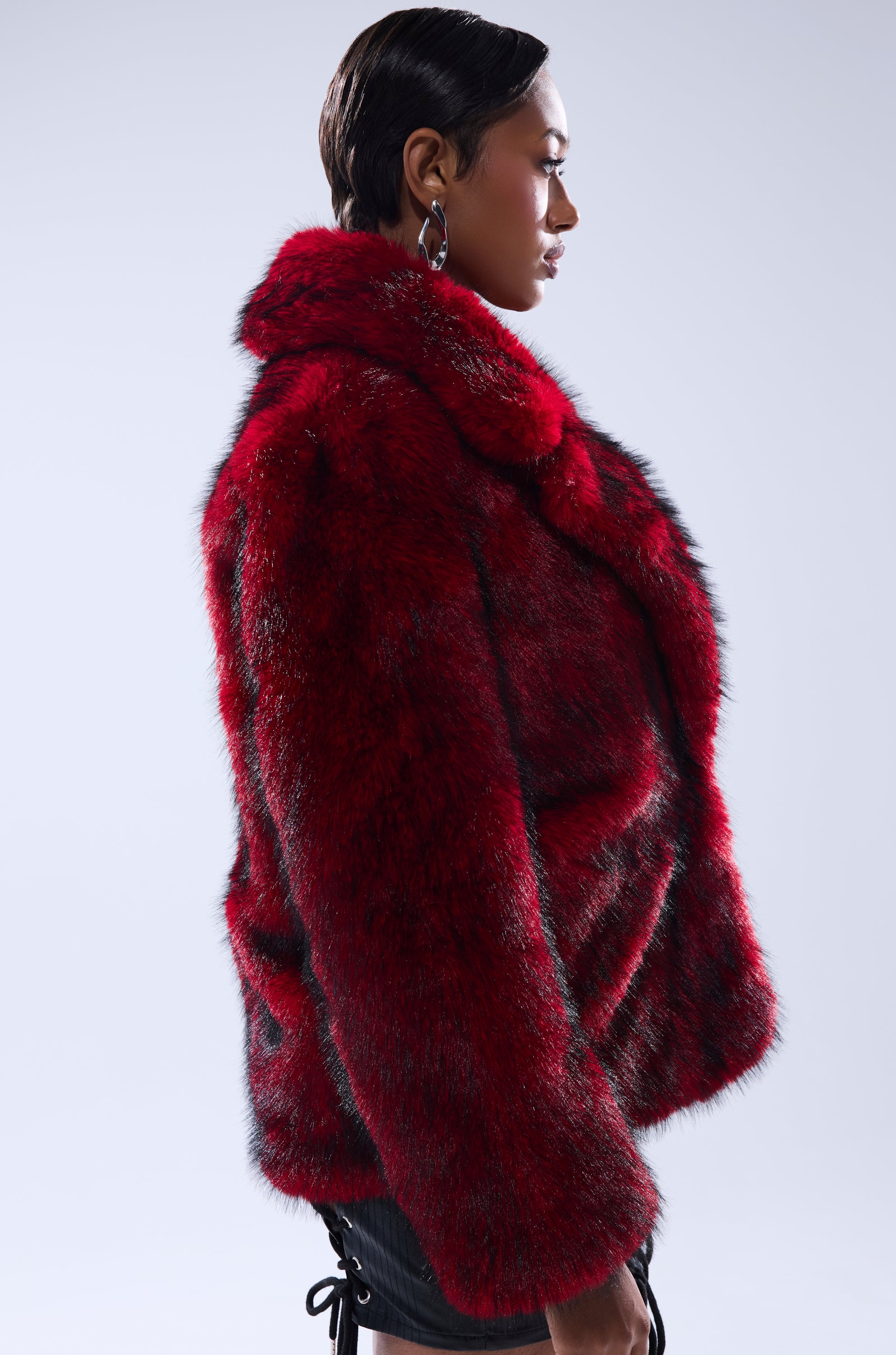 Wearing the NO LOOKING BACK FAUX FUR IN RED MULTI, a person with short, sleek hair stands in profile against a plain light background.