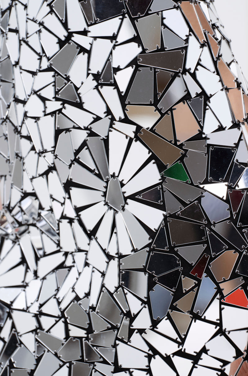 Close-up of the ALL EYES ON ME MIRRORED MINI DRESS, featuring countless small, irregular mirror pieces that create a fragmented, mosaic-like surface and beautifully reflect light and colors.