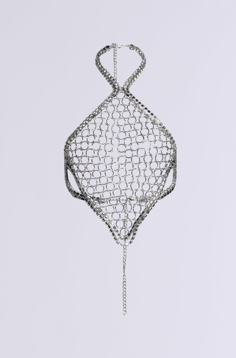 The IYKYK LUXE BODY CHAIN, showcasing a geometric, net-like design, is elegantly displayed against a plain background. This metallic piece features an intricate circular pattern with leg openings and is accentuated by its chain strap adorned with bling at the top and a dangling gemstone chain link at the bottom.