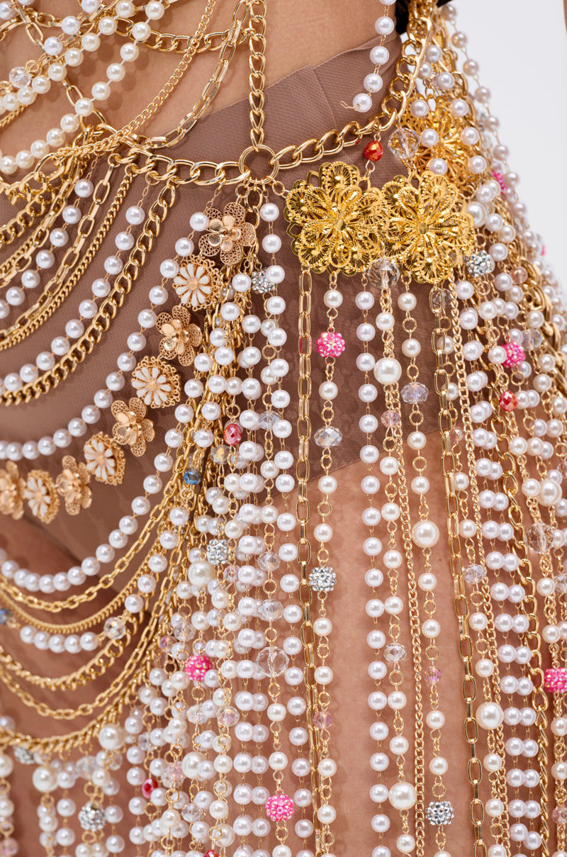 Close-up of the NAMIKA LAYERED CHAIN AND PEARL MINI DRESS, adorned with layered gold-tone chains, pearls, crystal accents, pink and silver beads, and detailed gold floral designs on sheer nude fabric.