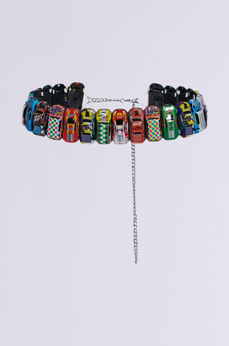 Introducing the FAST PACED CAR BELT: a vibrant and playful accessory featuring an assembly of miniature toy race cars connected side by side in a circular pattern. Each car is meticulously detailed, showcasing unique designs and colors that add to its charm. This belt includes a secure chain and clasp for fastening, making it an ideal statement piece for elevating any streetwear-inspired outfit. The product photos are set against a plain white background to highlight its intricate details. 4