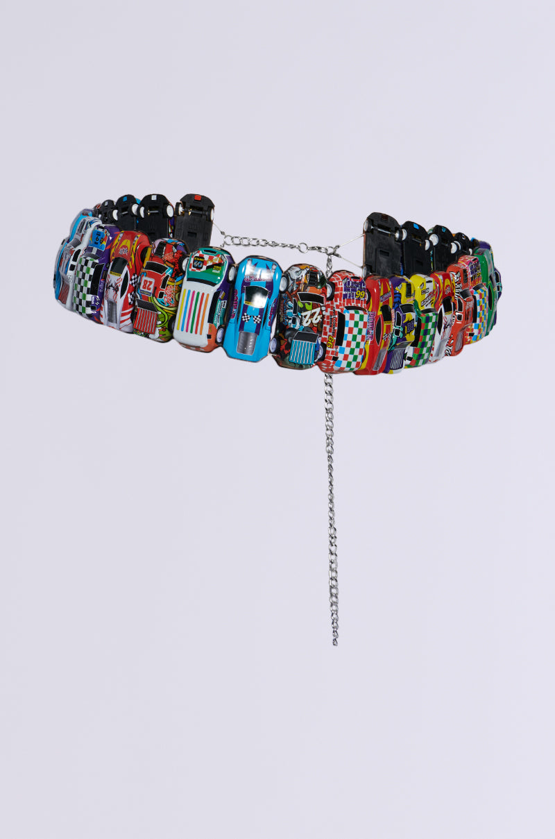 Introducing the FAST PACED CAR BELT: a vibrant accessory featuring an assortment of miniature toy race cars with dynamic designs. Perfect for adding a streetwear edge to your outfit, this belt comprises a sturdy silver chain complete with a dangling extension. The interconnected toy car models form an eye-catching circular pattern, displayed against a crisp white background.