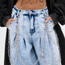 A trendsetter in light blue acid-wash jeans sports the PROUD OF YOU CLIP-ON PANT CHAIN, paired with a dark jacket and showing a "1999" plus eye tattoo on their stomach.