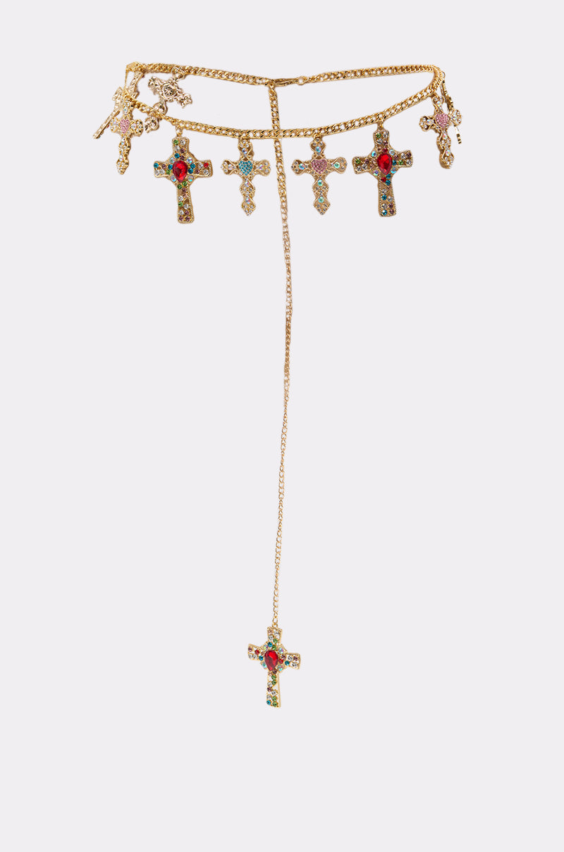 The IN MY FEELINGS CHAIN BELT is a gold chain belt featuring rhinestone accents, five small cross pendants with green, red, and blue stones, and a larger jeweled cross pendant on a longer chain. 1