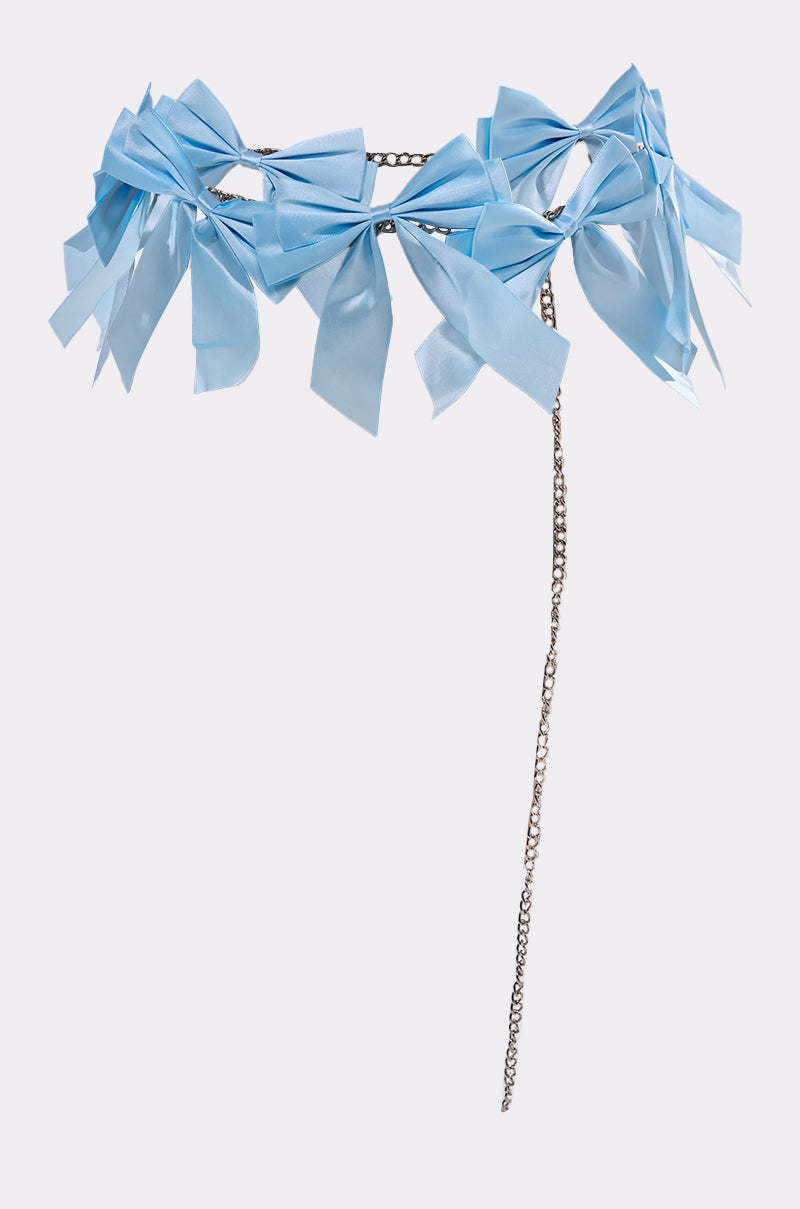 The FEMME BOW BELT features light blue fabric bows on a thin metallic chain with an extended drop chain, shown against a plain light background.